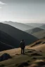 Placeholder: A man standing in the distance on a mountain looking out in the distance