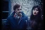 Placeholder: a young man and a beautiful woman standing next to each other, 1 9 8 0 s analog video, with mustache, small glasses, cold scene, out of focus background, house on background, the woman has long dark hair, photo realistic