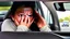 Placeholder: crying woman driving in hotel parking lot crying as she leaves to turn onto street