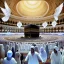 Placeholder: The scene in Mecca: People wearing white Ihram clothes, men without head coverings, women with veils, circumambulating around the Kaaba, and above them are transparent white spirits of children, men, and women with wings revolving around the Kaaba.