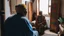 Placeholder: Two fifty-year-old people in traditional Moroccan clothing are discussing in the room of a Moroccan house, with only their backs visible