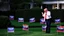 Placeholder: man in drag screaming on phone with trump 2024 campaign signs all over lawn