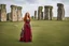 Placeholder: Full body shot of a tall slim red-headed young woman, dressed like a gipsy, standing in front of Stonehenge