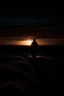 Placeholder: photo image of someone walking in the dark with a flashlight towards a faraway sunrise