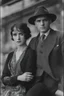 Placeholder: Up close Black and white photo of a serious couple sitting for portrait shoot in the 1920s