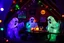 Placeholder: Glowing Halloween ghosts having a tea party in the haunted house attic. Colorful string lights and festive decorations create a spooky magical atmosphere