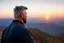 Placeholder: a brawny man with grey hair views sunset from a cliff