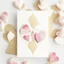 Placeholder: A photo of a white card, 5.5 by 4.25 inches. The card is vertically positioned on a beautiful white surface, positioned between rose petals and litte golden hearts.