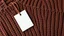 Placeholder: White paper tag on a brown woolen sweater