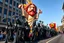 Placeholder: 200 ft tall cartoonish jesus parade balloon pulled by multiple grim reapers, multi colored, bright, vivid, psychedelic, high detailed, high gloss, insanely detailed, matte, horrorcore, lining the street, unsettling contrast, monument to death, live action shot grim reaper parade, pulling a jesus parade float