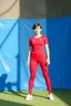 Placeholder: A full-body shot of a beautifulazeri lady in red futball suit and pants short hair standing idle pose front to camera