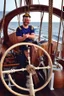 Placeholder: a cheerful sailor sitting on rum barrels aboard a sailing ship at sea, with the ship's steering wheel in the background