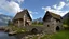 Placeholder: small gothic medieval house built into a rock face, lake, trees, arches, bridge, foliage, balconies, verandas, blue sky, white clouds