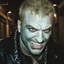 Placeholder: very grainy discolored 2000s photo, closeup portrait, dark night alley with no lights, grunge, extremely gaunt male with chalk-white skin wearing a leather jacket with chains, angry, imposing, bald, fiery look in the eyes, bruja