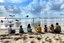 Placeholder: families sitting on a beach lagoon, birds in the sky