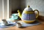 Placeholder: knitted teapot with china cup in a modern kitchen isn sunshine