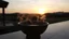 Placeholder: reflective ceramic bowl of steaming liquid, sunset in background, photographic image, realistic, surrealism