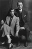 Placeholder: Black and white photo of a serious couple sitting for portrait shoot in the 1920s