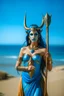 Placeholder: A picture of a beautiful blue faced indian goddess with skin painted blue, blue painted body, blue painted torso, wild black hair, stag antlers, elven ears, golden skirt, holding a staff on a sunny beach