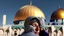 Placeholder: A woman wearing a keffiyeh hugs the Dome of the Rock with her hands