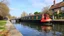 Placeholder: Historic traditional English canal barge, long boat on an English canal. The boat is beautifully painted in an ornate, colourful traditional style. It is approaching a canal lock. Award-winning colour photograph.