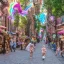 Placeholder: A magical street, a cobblestone street, shops and vendors on both sides of the street, unicorns on the street, little forest fairies flying, a minotaur eating ice cream, a baby gorgon playing soccer.