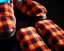 Placeholder: Red plaid slippers on black bearskin rug,log cabin walls, stone fireplace