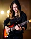 Placeholder: attractive woman(wearing a dark hoodie of light material) playing an electric guitar at vertical angle