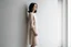 Placeholder: Woman wearing a wool dress, leaning against a white wall, fashion photography, real photography,16K