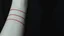Placeholder: monochrome photo of a pale colored forearm on which three parallel thin red marks can be seen crosswise, in the background depth, shadows, darkness, close up arm, sad, surreal dark vibe, dark colors, splash art, cinematic, depressive vibe