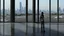 Placeholder: Tall thin woman, with straight black hair, dressed in a camouflaged jumpsuit, looking out from the rear of a futuristic aircar, on a tarmac runway, with a city skyline in the distance