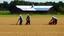 Placeholder: young and old people working in the field near medieval barns