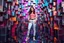 Placeholder: beautiful lady with todays modern clothing and sport shoes, in surreal stage made of fractal random size objects with helical strip colors in clothing similar to environment full body posing to camera,animating background metallic random color cubes