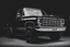 Placeholder: front corner 1973 Chevrolet square body truck(lifted) facing a little to viewer's left, dark gray background, high contrast black and white vector