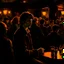 Placeholder: a single figure in a crowded bar at night, young people, dark colors, rembrandt style