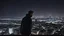 Placeholder: An Englishman in a bomber jacket standing at the top of a tall building looking across a city at night