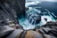 Placeholder: massive intimidating rock cliffs ascend all around and further up out of view. far below, the stormy ocean swirls intimidatingly. The ocean water falls off a waterfall down into a circular pit