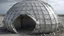 Placeholder: Collapsed shell — dome that partially sinks according to a weakening algorithm; deformed panels; open joints; gray-opaque atmosphere; data-generated sense of ruin.