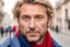 Placeholder: a man 40 years old, without a beard and no wrinkles on the face, blue eyes, blond hair, very handsome, with a blue jacket and red scarf, in background Paris