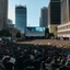 Placeholder: A crowd watches a giant screen in the middle of the city