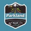 Placeholder: logo for a shop that installs tires and does oil changes, top has elements of beautiful park highway drive, bottom shows the engine under car hood. on hood is written "Parkland", all inside a shield shape with squared top and rounded bottom, in the style of national parks stickers