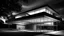 Placeholder: Mies van der Rohe-influenced contemporary residential home featuring clean lines, open floor plan, and extensive use of glass and steel, high detail, black and white monochromatic palette, grey scale, dramatic dutch light