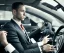 Placeholder: Man in suit, sitting at the wheel of his car, looking exhausted, tie untied, chin thinning