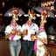 Placeholder: very Gay Giraffes sailors with white shirts and berrets and tight jeans standing in a bar drinking drinks with umbrellas, pride, makeup, smoking ciggarets, smiling, sparkling eyes, very happy, after dark, pink scarf, happy hour drinks sign, necking, happy cock hour