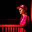 Placeholder: woman with a red baseball hat. leaning on a wooden balcony.night time. studio lightining.