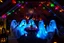 Placeholder: Glowing Halloween ghosts having a tea party in the haunted house attic. Colorful string lights and festive decorations create a spooky magical atmosphere