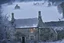 Placeholder: Snow falling heavily in the Cotswald area of England. A stone cottage with smoke coming out of the chimney. Surrounded by stone fences. In the background a startled group of deer look this way. A thick forest behind them.