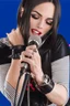 Placeholder: attractive female country music singer leaning forward while holding microphone in one hand, other hand brought up to side of neck, change clothing to plaid in natural tones, leather bracelets on wrists, long hair, mouth open singing, rings on fingers, eyes closed