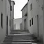 Placeholder: Street of a town on an Italian island in summer, with stairs and arches, decadent tone, real photography, photography taken with a Leica camera and 50 mm lens, following the style of the 'Ripley' series, black and white photography, toned 50s tones