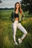 Placeholder: fullbody shot of young-beautiful-girl-with-a-perfect-face wearing sport pants and thight blouse and jacket shoes standing in country side green field day lights